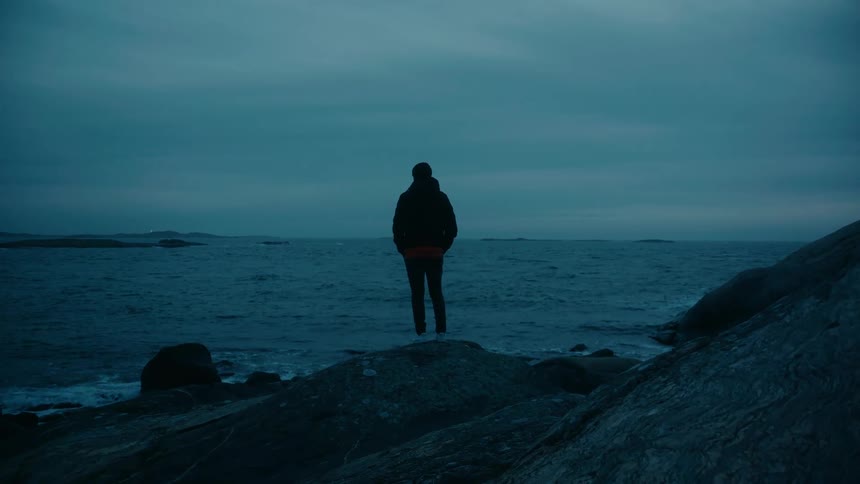A man is standing and looking at the ocean