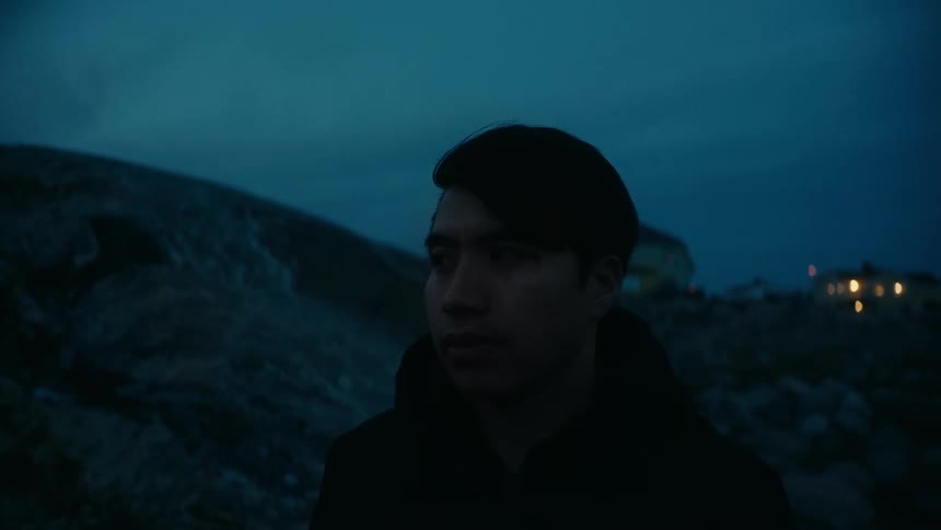 A young man is standing outdoors in the middle of the day