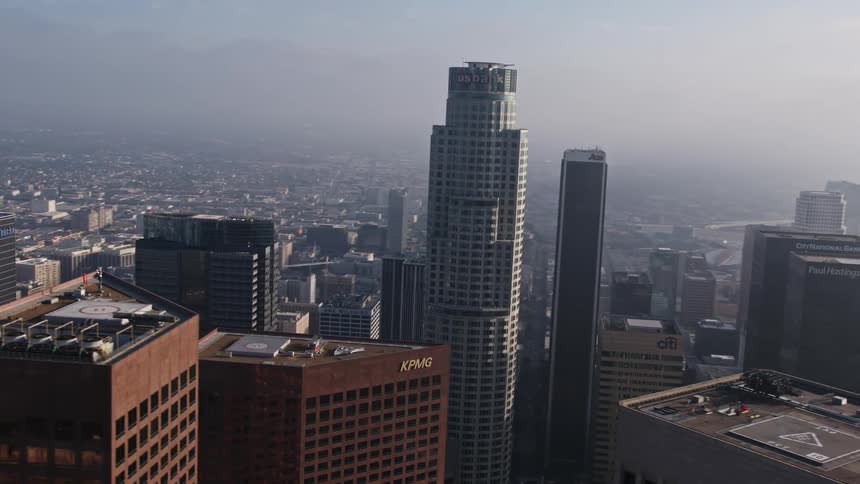 This 4K aerial stock footage orbits the US Bank Tower in Downtown Los Angeles California showcasing the high-rise building amidst the hazy and foggy cityscape