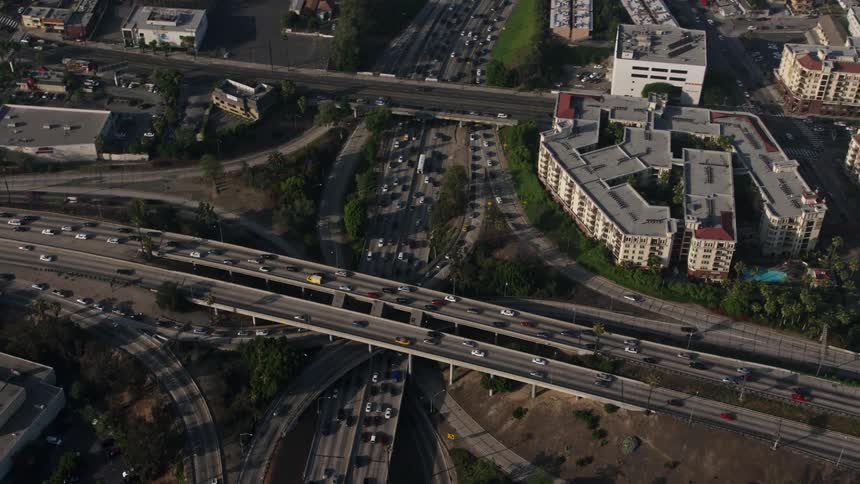 4K aerial footage of freeway traffic on the I-110 and 101 interchange followed by a pan towards downtown LAs apartment buildings on a hazy day