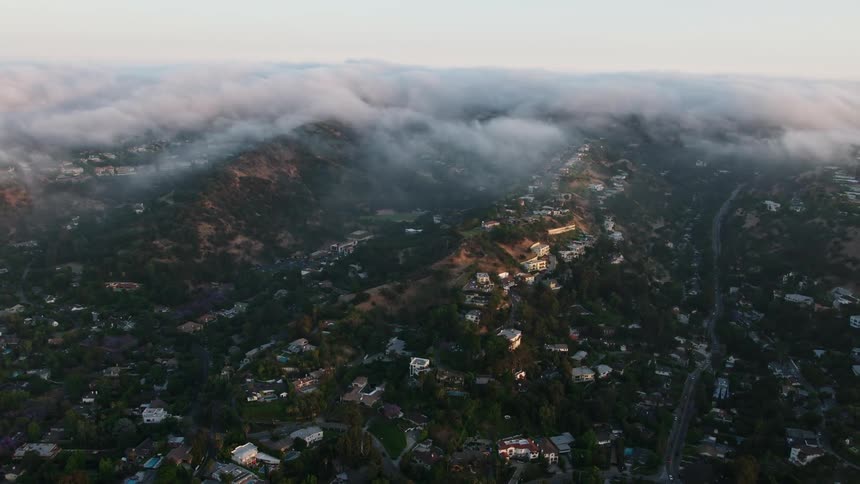 Upscale hillside homes draped in fog during sunset over Sherman Oaks California in 4K aerial footage