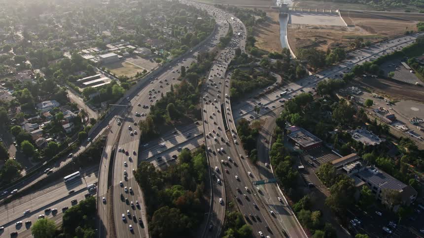 A 4K aerial view of heavy traffic on the I-405 and 101 interchange in Sherman Oaks California with office buildings and the Sherman Oaks Galleria visible in the background