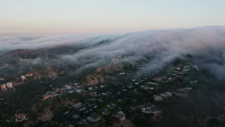 Aerial footage of a marine layer engulfing residential areas in Studio City California during sunset