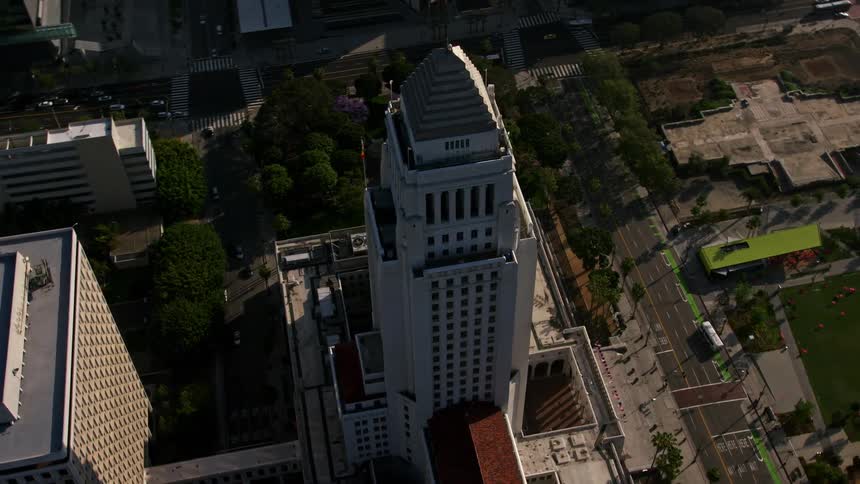 Aerial footage of Downtown Los Angeles City Hall orbiting over the metropolis with bright sunshine and clear blue skies during a California daytime