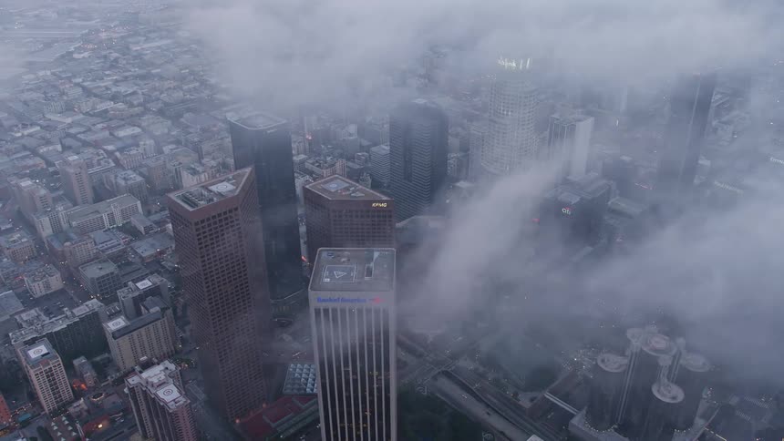 Aerial footage of high rise towers and skyscrapers covered in marine layer during twilight in downtown Los Angeles