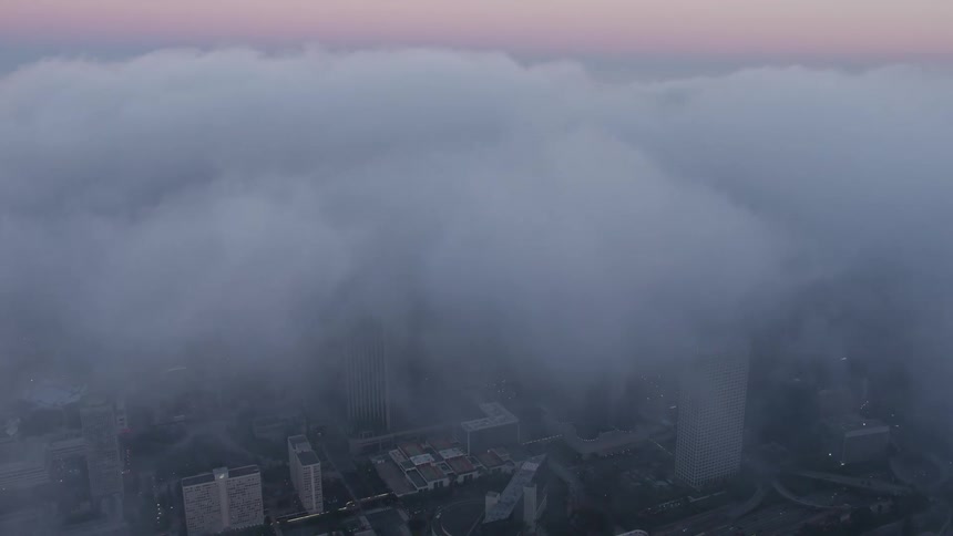 A stunning 4K aerial shot of Downtown Los Angeles at twilight covered in a dense fog with a tilt down revealing the towering US Bank Tower