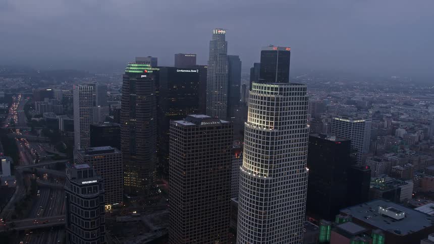 Aerial view of skyscrapers in downtown Los Angeles surrounded by a marine layer during twilight