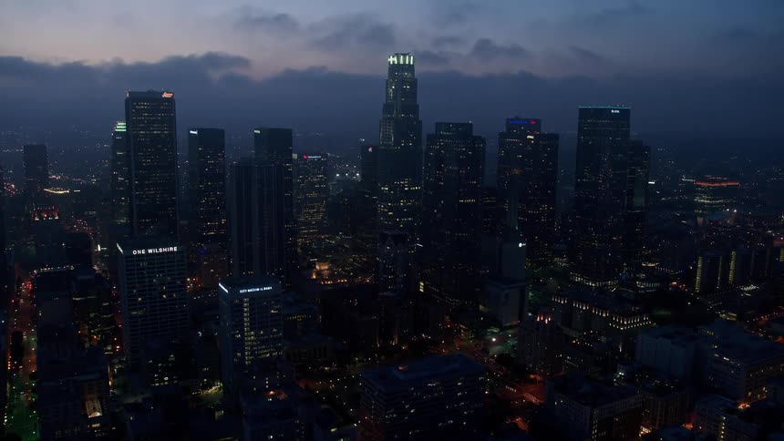 Flying over Downtown Los Angeles at twilight this 4K aerial footage showcases the citys high-rise buildings surrounded by a marine layer