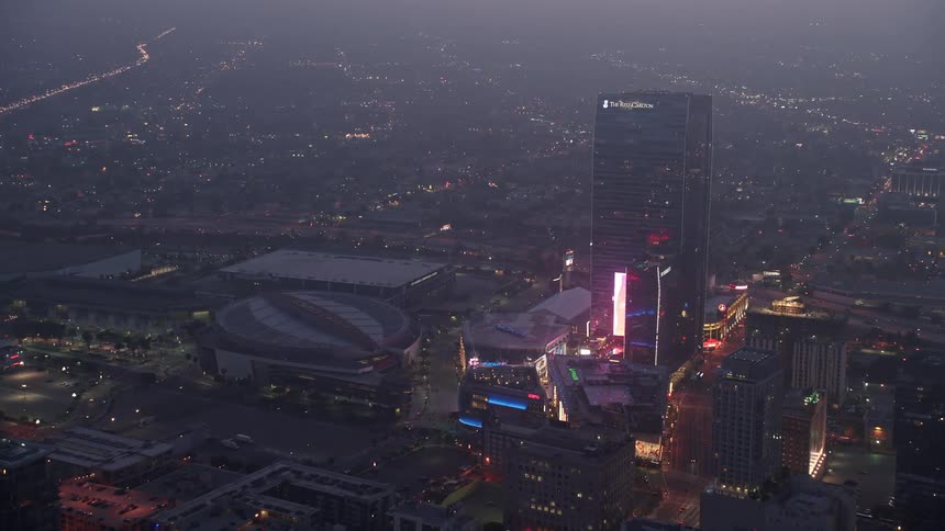 Approaching Staples Center and panning to The Ritz-Carlton Los Angeles during twilight with fog rolling in - showcasing the lively downtown area