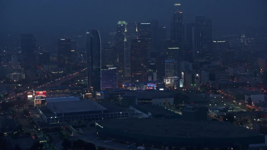 Aerial view of downtown Los Angeles skyline during twilight revealing itself as the camera tilts up from the interstates