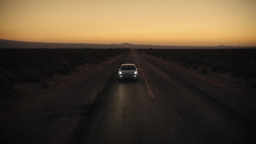 A car drives down a deserted highway at night