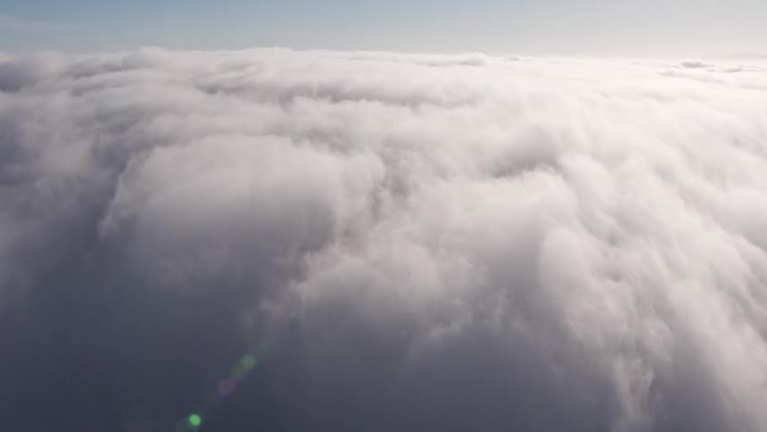4K aerial footage panning over and through dense marine clouds blanketing Los Angeles revealing the bright sun above