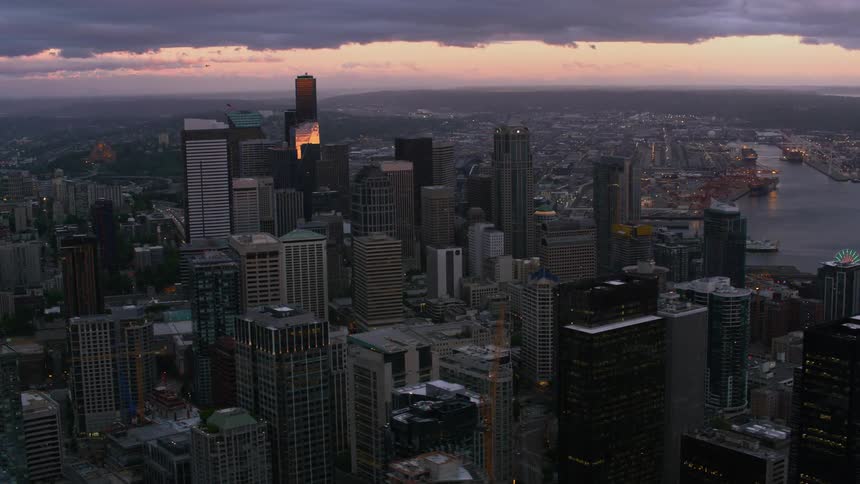 A drone in the air captures a large city with buildings everywhere and a sky with looming gray clouds