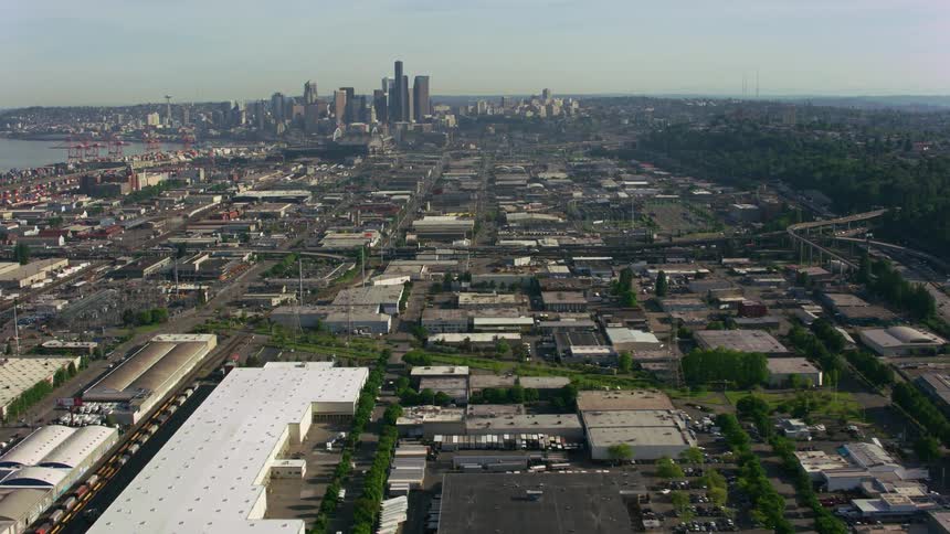 Traffic winds past warehouses and the loading dock on the way to the city skyline