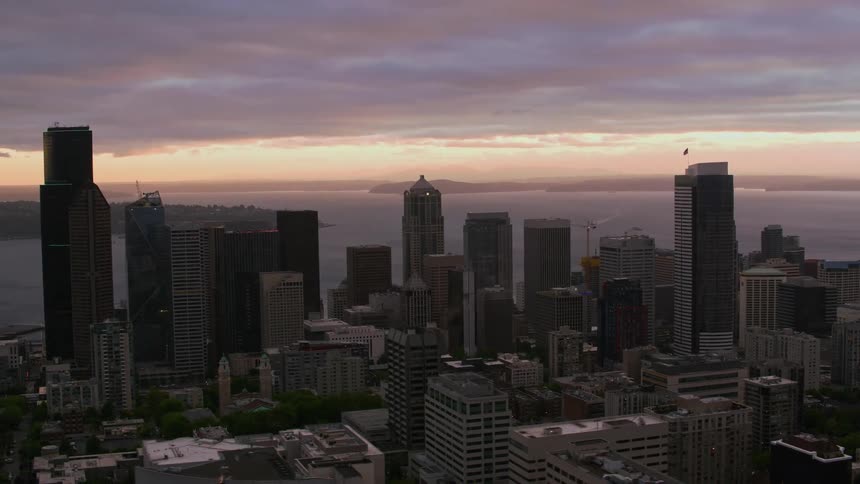 An aerial view of a downtown city center with skyscrapers along the waterfront at dusk