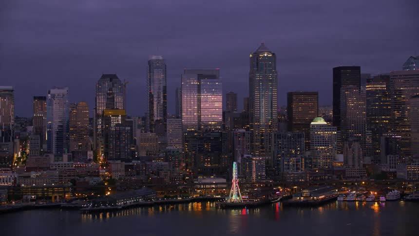 A ferris wheel is lit up at night along a downtown coast