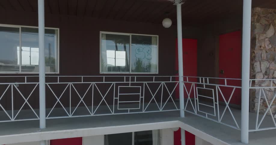 Slow push toward the window of an upper level room scrawled with graffiti