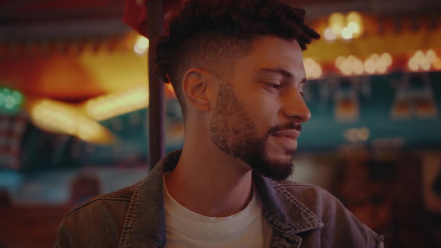 A man chats with someone at an amusement park