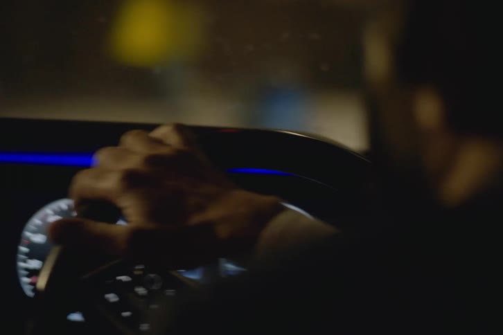 A man uses both hands to turn the steering wheel while driving
