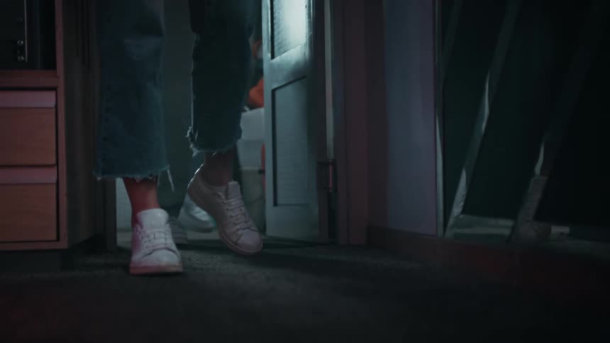 Man and woman in jeans and white sneakers open door and enter room slowly