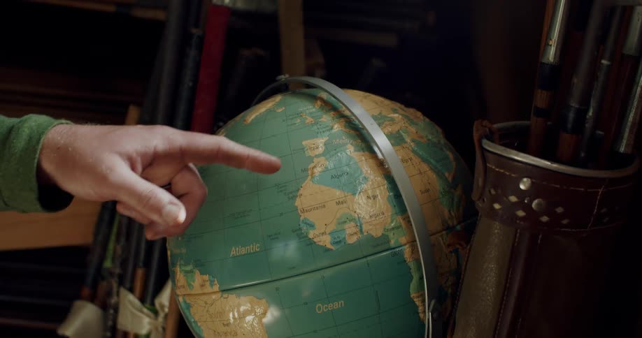 A hand points to places in a globe map of the world then spins it with a finger