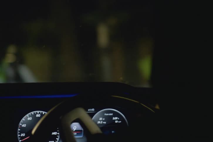 Man drives car along street at night