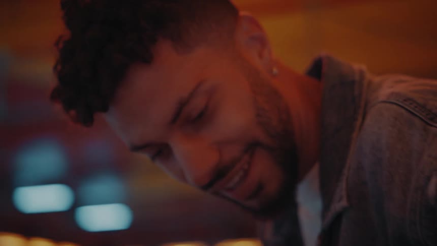 Man smiles downward while talking in arcade
