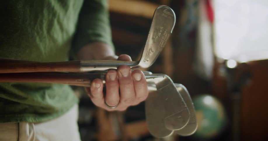 A person is holding golf clubs