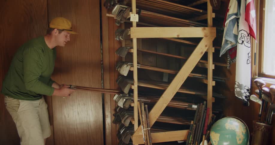 A man grabbing golf clubs off a rack with multiple other golf clubs