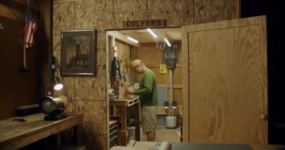 A man does woodworking in a basement studio