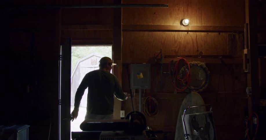 Man wearing cap walking by and turning off the lights before he leaves through the door
