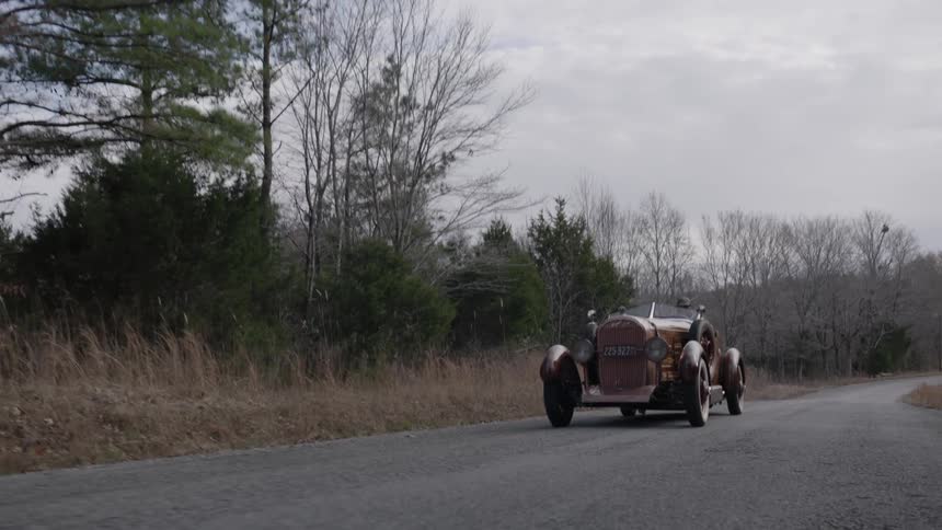 A vintage car drives on the road