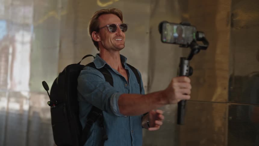 A man uses a selfie stick to record himself on his phone while walking