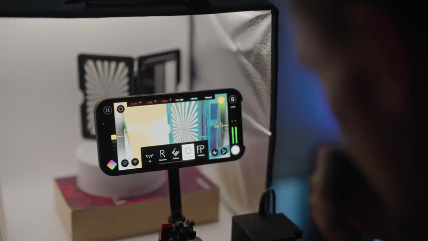 A man is operating a camera as he records an object rotating inside a machine