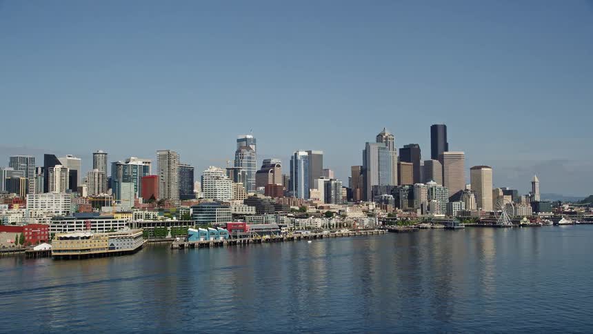 A mesmerizing aerial view of Seattle's downtown skyline and bustling Central Waterfront piers showcasing the vibrant metropolis and its lively harbor during a sunny day