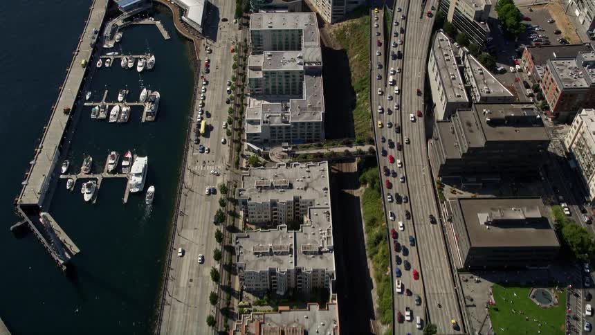Bird's eye view of piers and apartment buildings on the Central Waterfront in Downtown Seattle Washington with traffic and a bustling metropolis backdrop