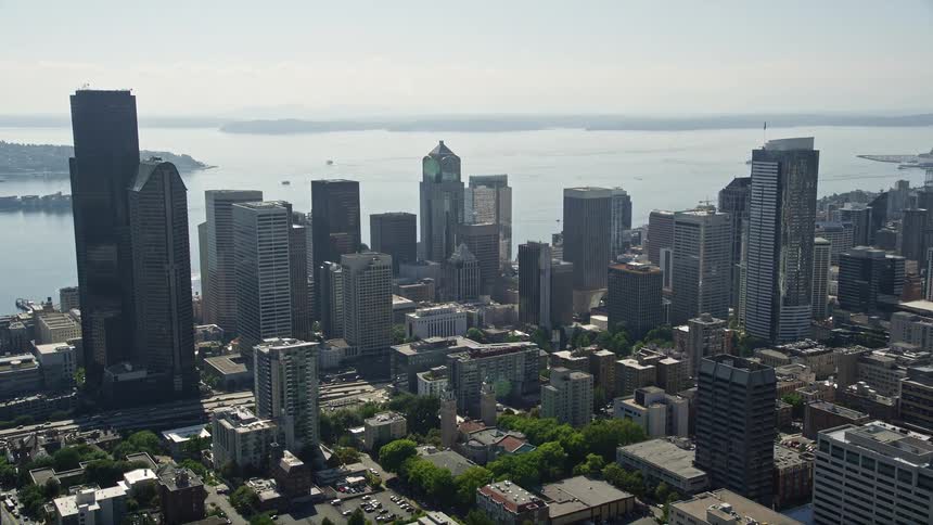 Aerial view of downtown Seattle Washington flying over the city to reveal the Central Waterfront on a sunny day