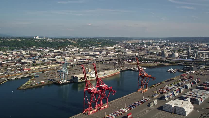 Aerial footage of cargo cranes and shipping containers at Harbor Island Seattle WA with a sunny and industrial atmosphere