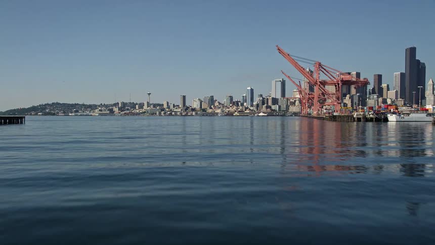 Aerial flyby of cranes over the Duwamish Waterway at Harbor Island capturing the high-rise skyline of Downtown Seattle