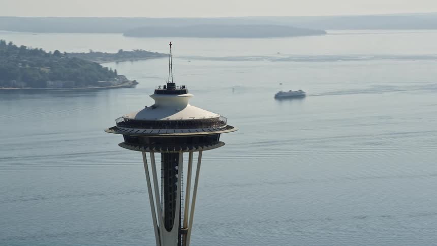 Aerial footage of orbiting around the iconic Space Needle in downtown Seattle Washington capturing the city's famous landmark and vibrant atmosphere on a sunny day