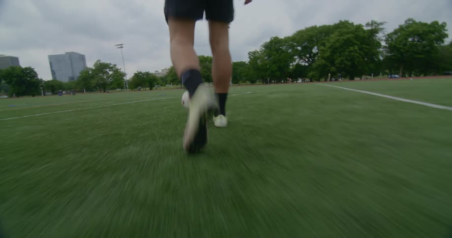 A person walking up to kick a soccer ball on a field