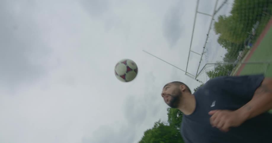 A man hits a soccer ball in their air with his head