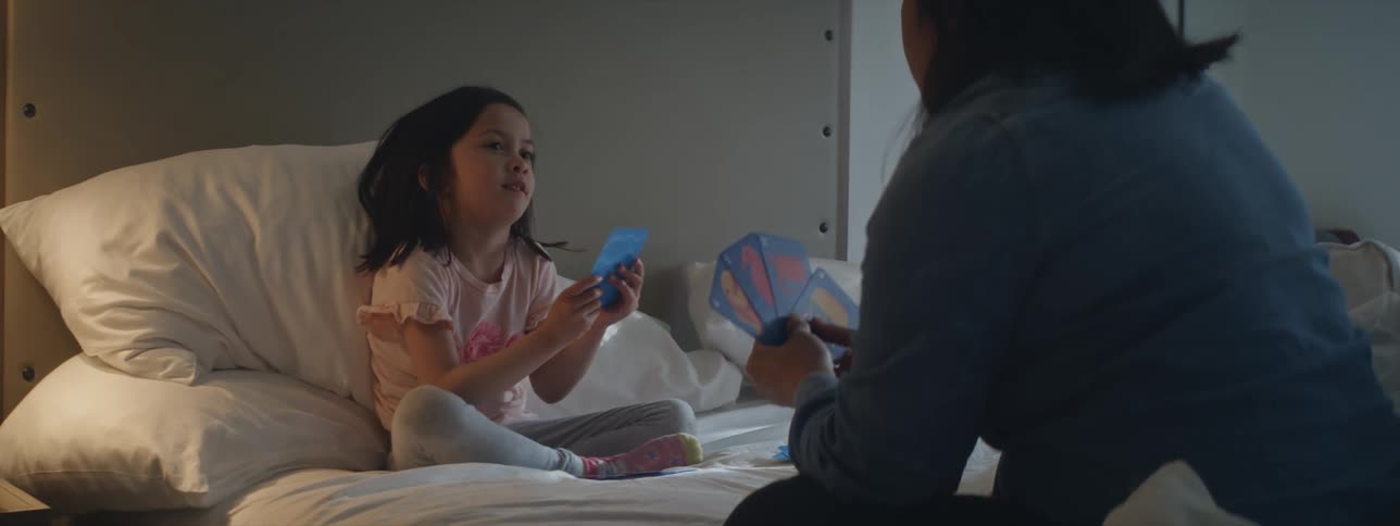 A girl plays a card game with her mom