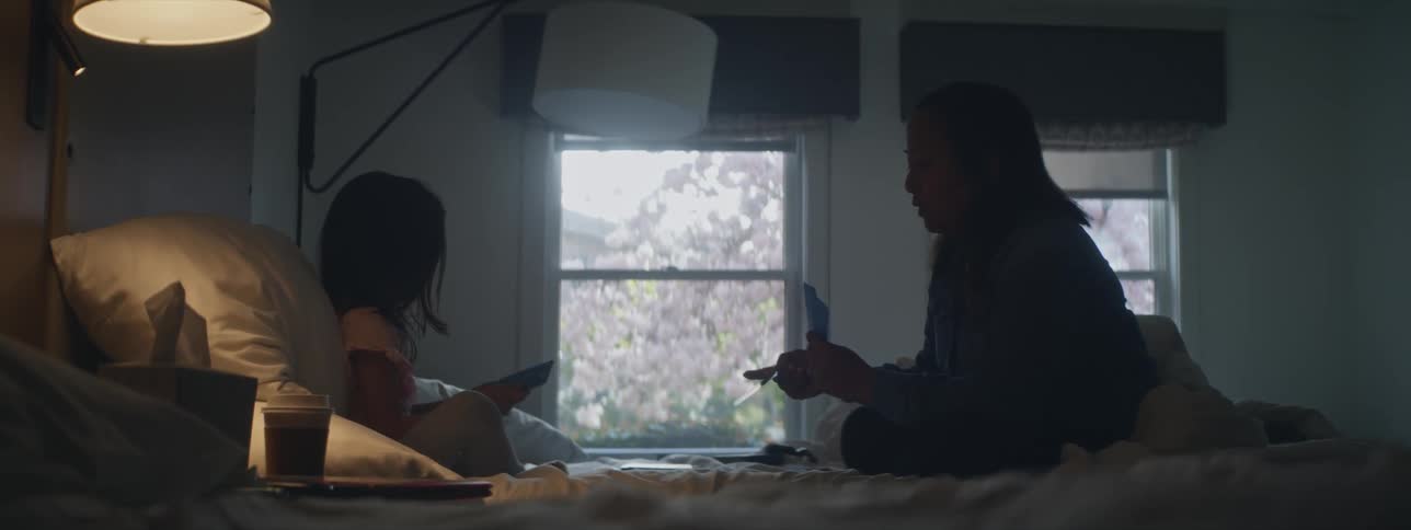 A mother and daughter play cards in bed