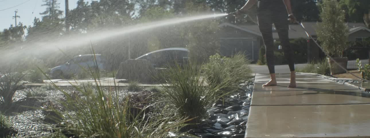A woman waters her front lawn