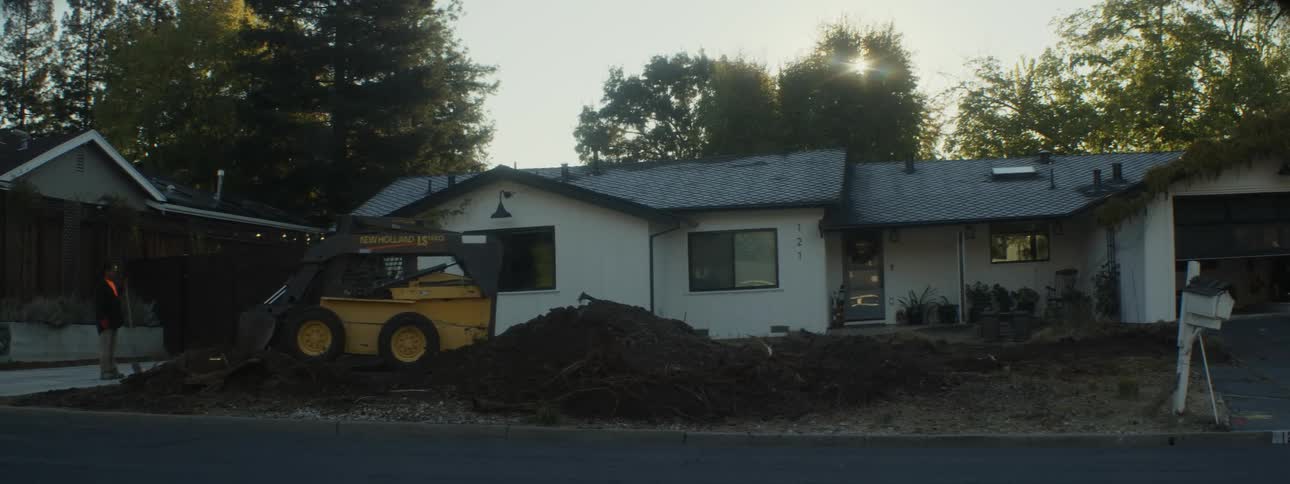 A bulldozer is used to remove dirt in front of a house