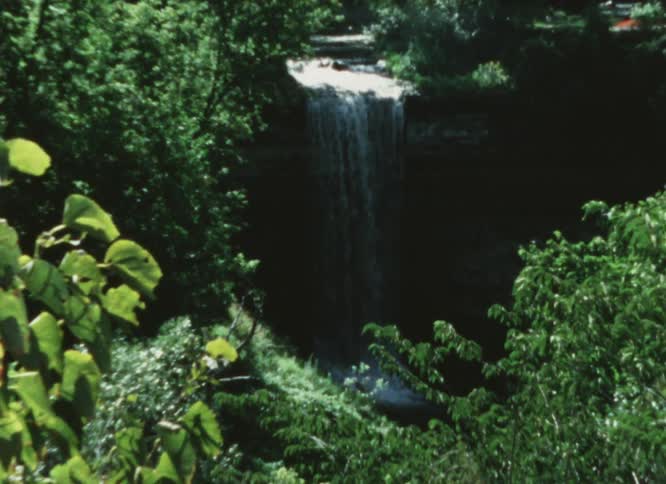 Waterfall flows down cliff in forest