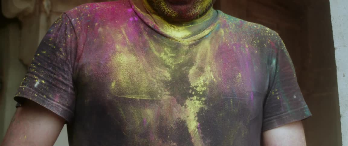 Close up of a man shaking off colored dust from his shirt