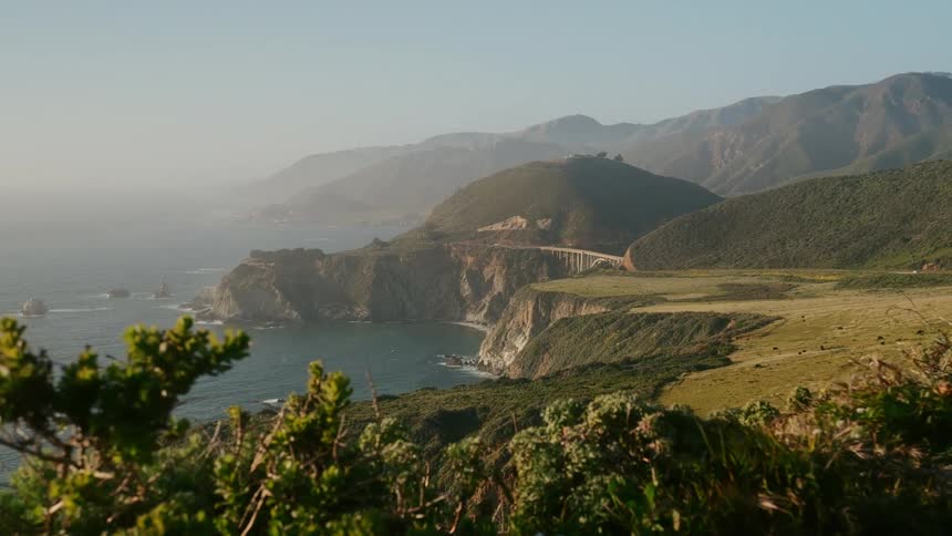 A coastal area with a grassy field and hills leading into cliffs