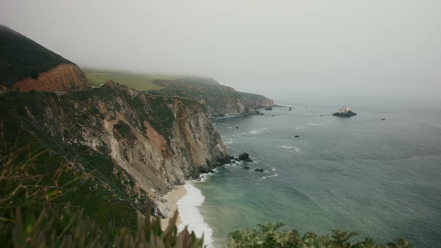 Waves crash onto the beach below tall cliffs